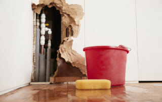 Water Damage Restoration - Bucket and Sponge next to Wall with Water Damage