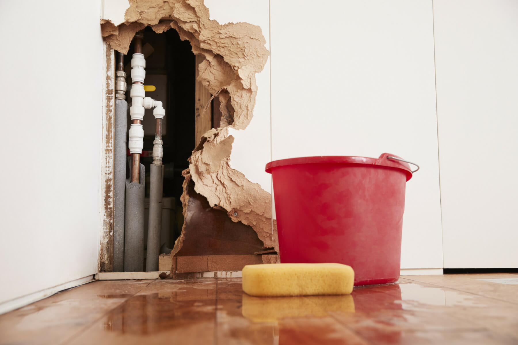 Water Damage Restoration - Bucket and Sponge next to Wall with Water Damage